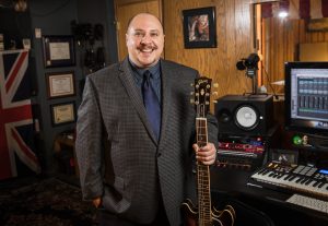 Music industry professional posing with guitar in music studio
