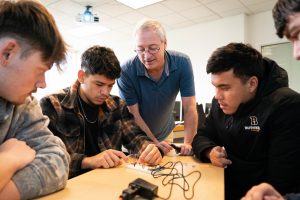 Computer science students working on an electronics project with professor guidance in a classroom