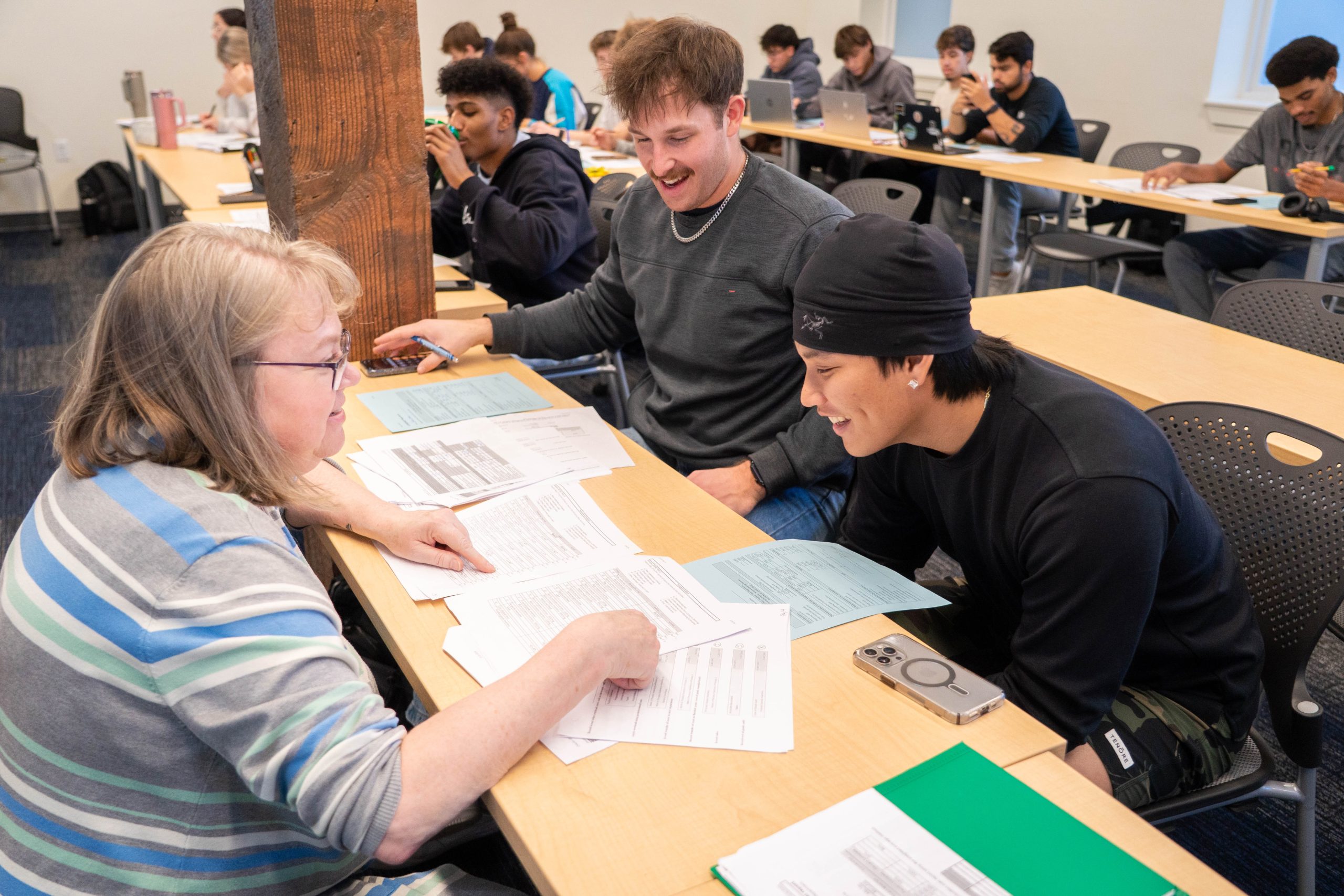 professor assisting students on finance worksheets in class