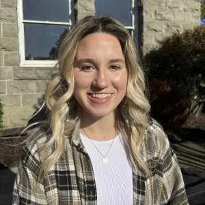 Headshot of a female student on campus with a plaid shirt in the sun