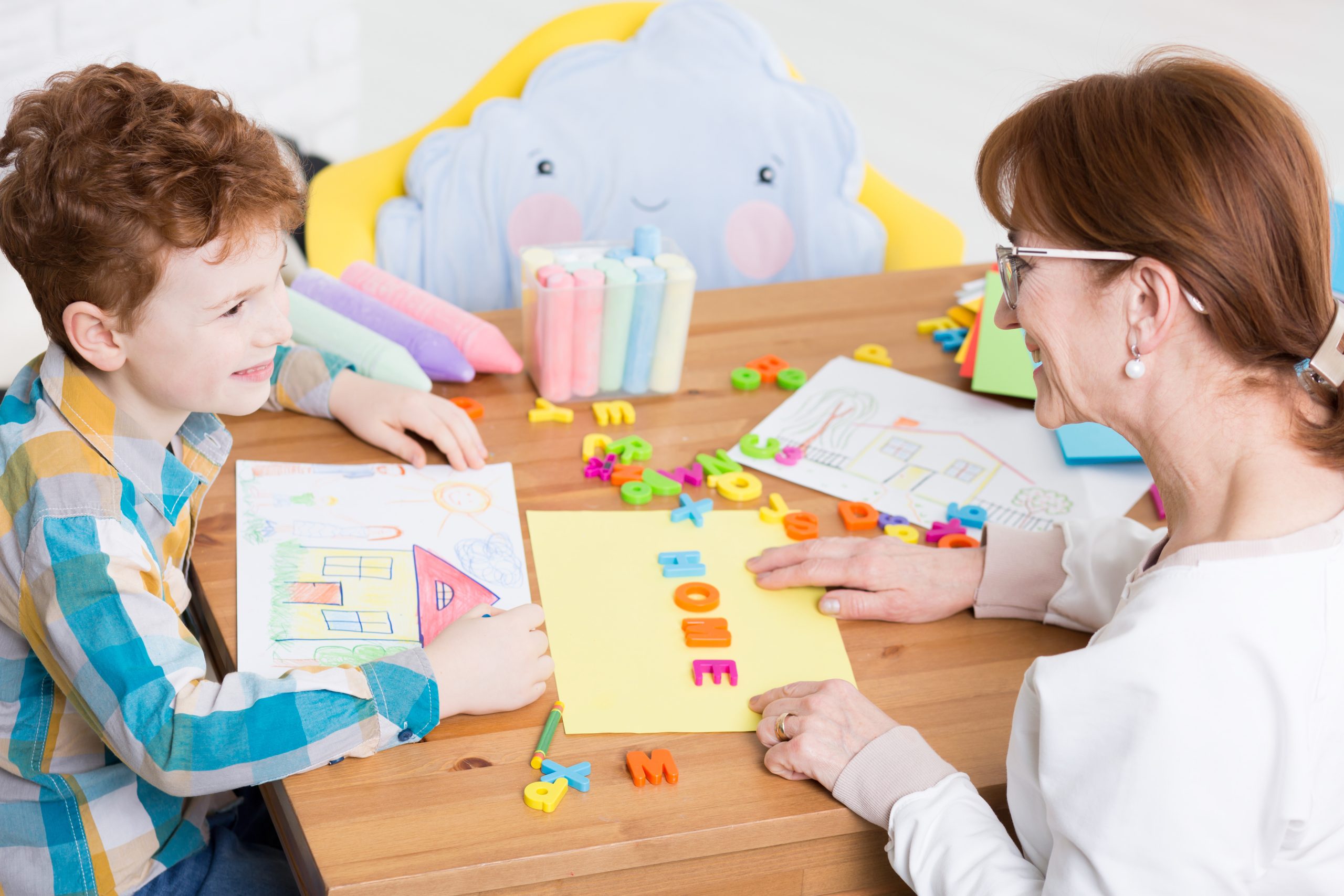 School counselor helps a young student sort out their thoughts through activities like drawing.
