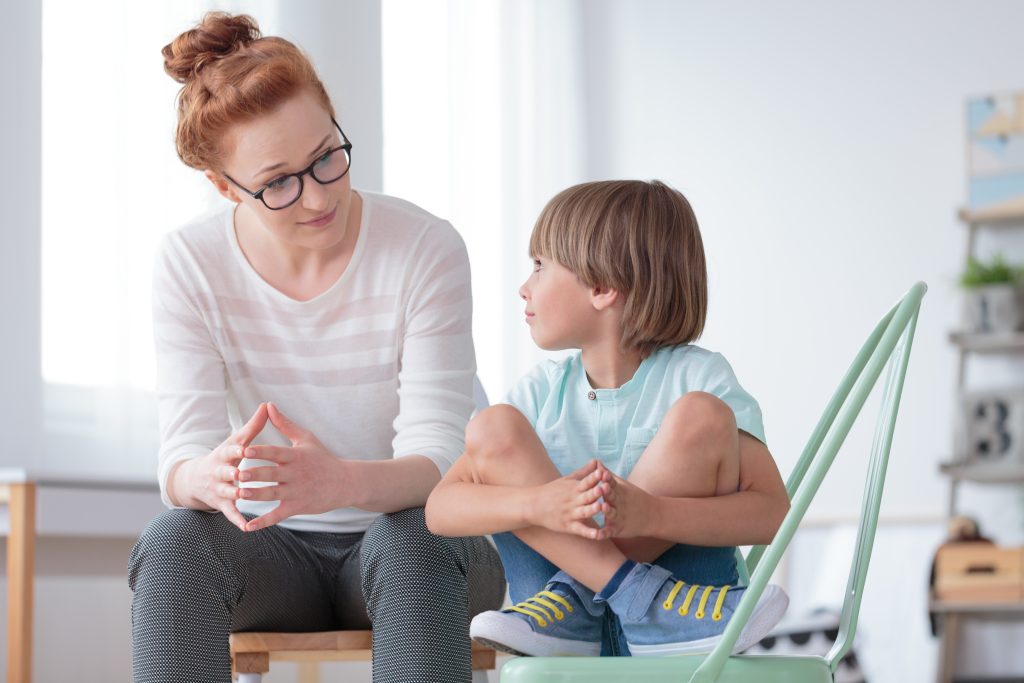 School counselor having a conversation with a young student in office
