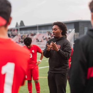 Young male soccer coach instructs players during a soccer game