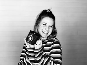 Female student smiles while holding a coffee mug