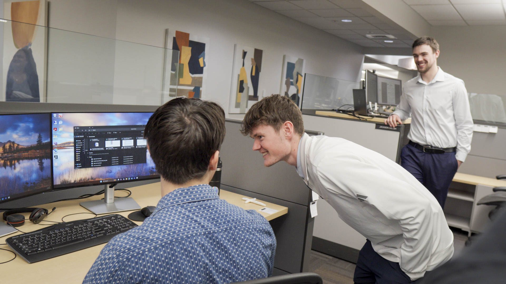 Student interns working together at computer monitors in an office setting