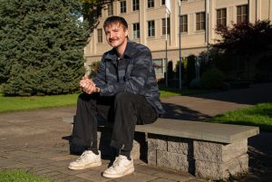 Male ministry student sits on a bench on Bushnell campus in the sun