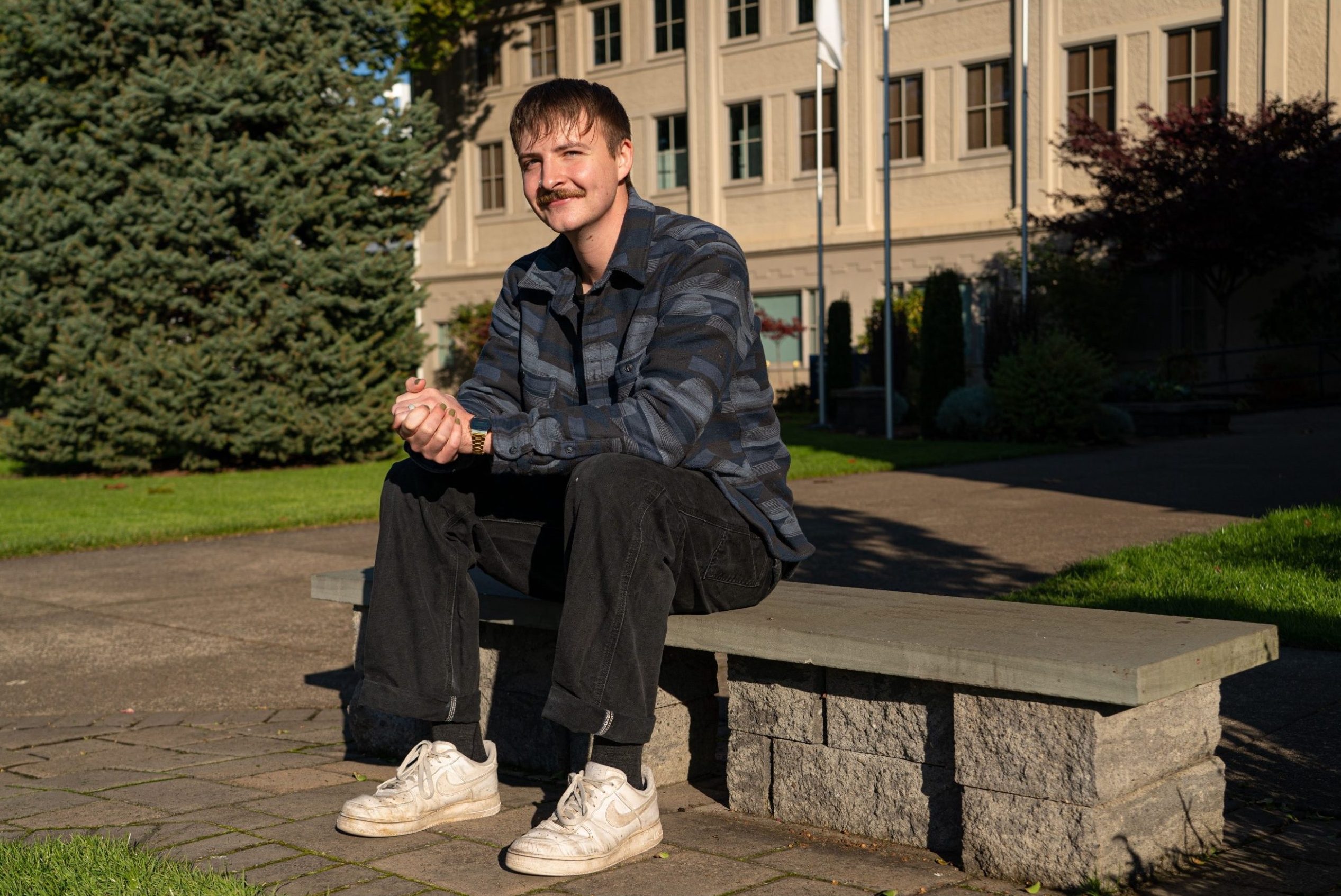Male ministry student sits on a bench on Bushnell campus in the sun