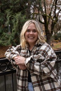 Female student in plaid shirt poses outside in the fall