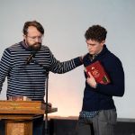 Professor prays over a student holding a gifted bible