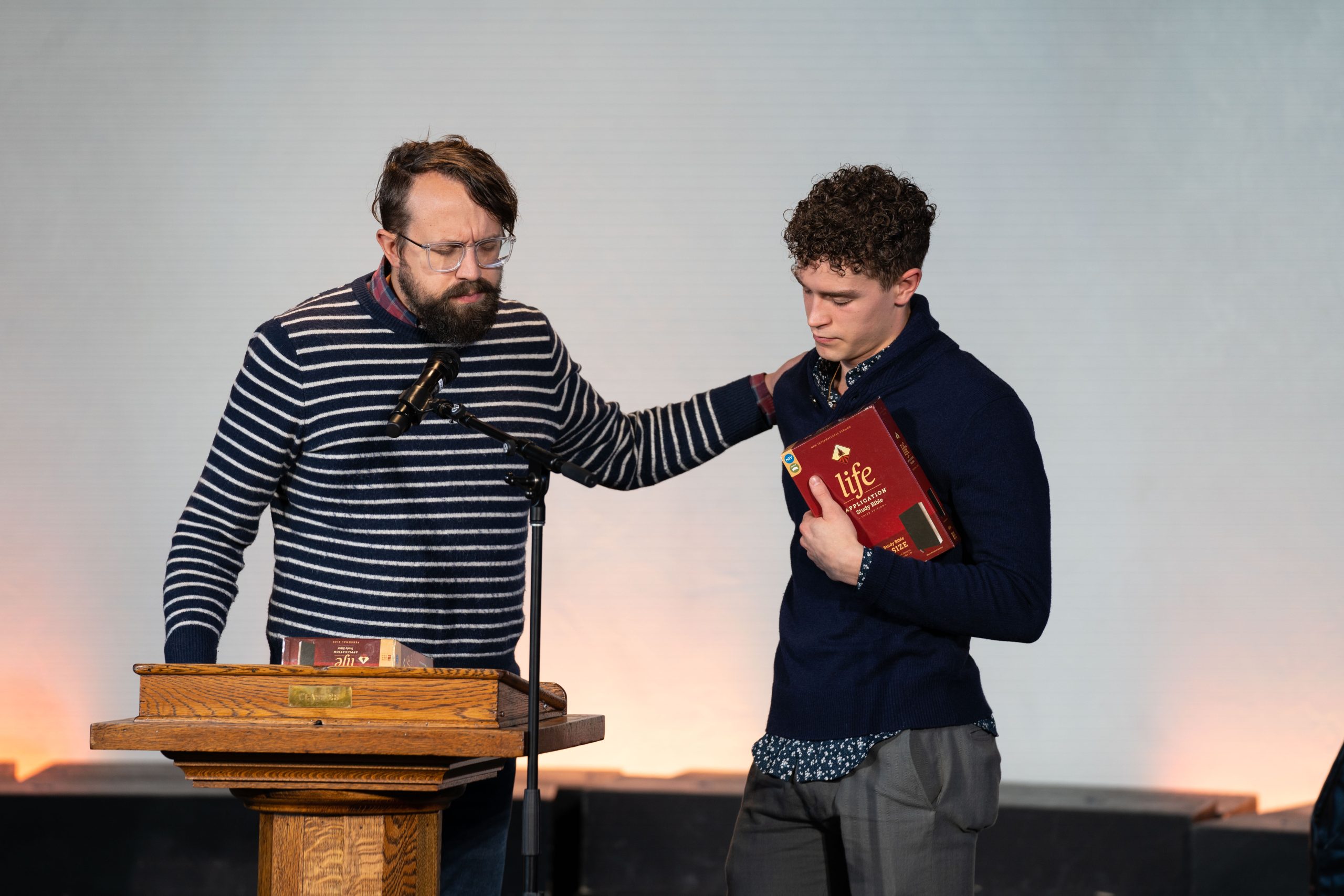 Professor prays over a student holding a gifted bible