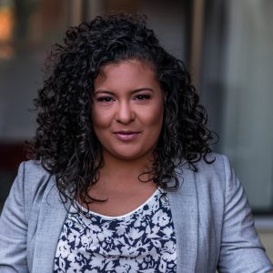 Professional headshot of an educator in a grey jacket