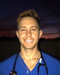 Male vet tech smiling with cross necklace during sunset