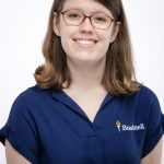Bushnell University staff member smiles for a professional portrait while wearing a Bushnell polo shirt.
