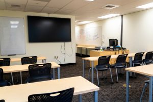 Modern nursing classroom featuring collaborative seating, a large digital display, whiteboard space, and instructor workstation.