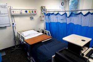 Simulated hospital patient room with a hospital bed, medical equipment, and clinical training resources for nursing education.