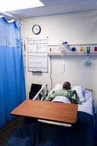 High-fidelity patient simulator positioned in a hospital bed within a nursing skills and simulation laboratory.