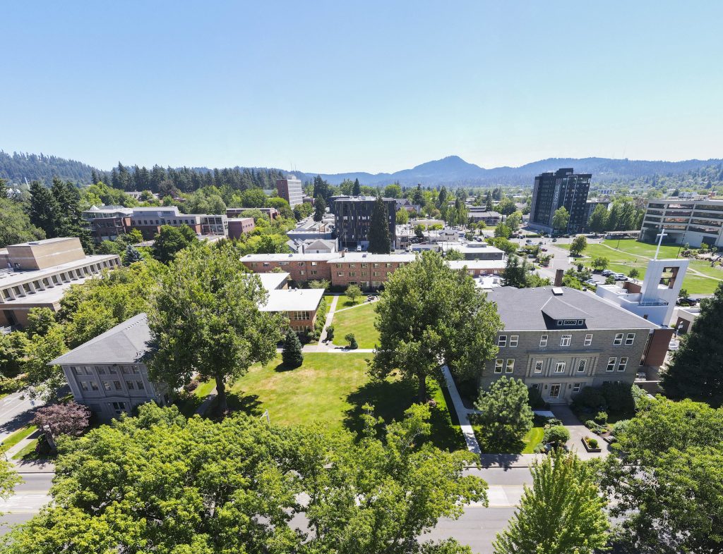 Aerial view of Bushnell University campus with academic buildings, green spaces, and the Eugene hills in the background.