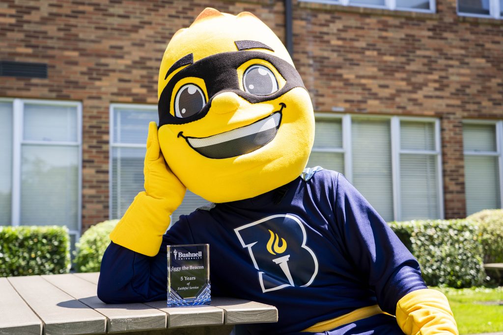Iggy the Beacon, Bushnell University's mascot, poses with a service recognition award during a campus employee appreciation event.