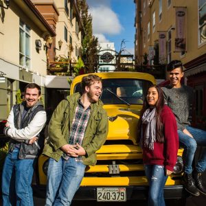 A group of Bushnell University students gather in downtown Eugene near a vintage truck during a community and student life activity.