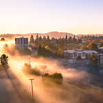 Morning fog and sunlight surround the Bushnell University campus and surrounding Eugene neighborhood at sunrise.
