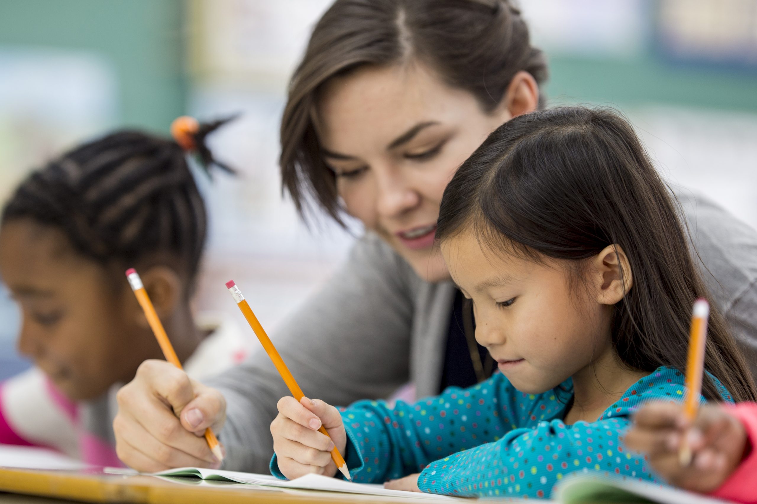 Teacher providing one-on-one reading support to an elementary student during a literacy lesson.