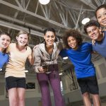 Teacher leading a group of elementary students during a physical education lesson in a school gym.