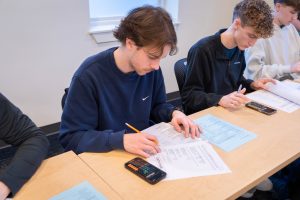 Students in class perform calculations while working on finance worksheets.