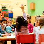 Teacher leading an elementary classroom discussion with students gathered around a table.