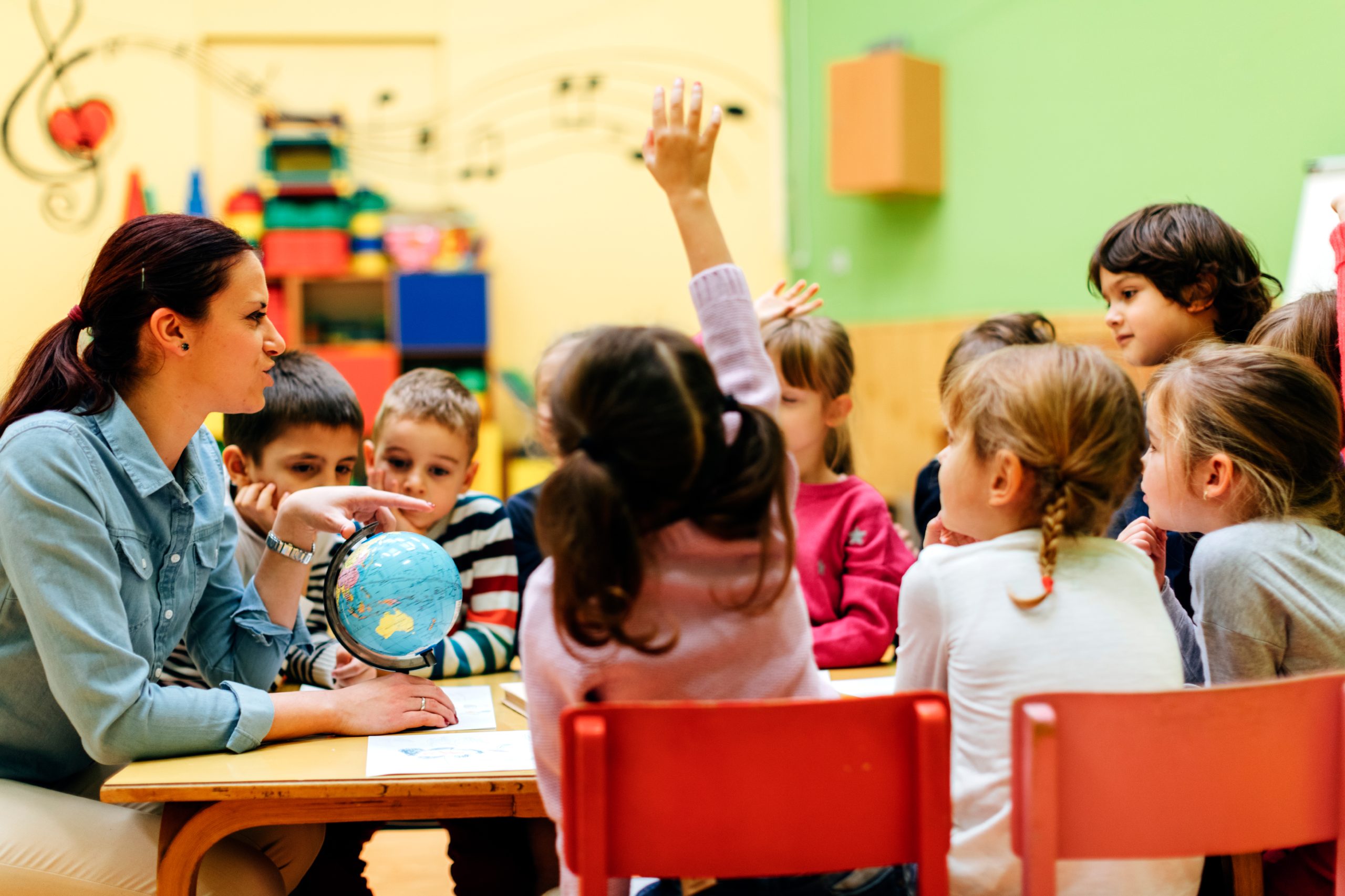 Teacher leading an elementary classroom discussion with students gathered around a table.