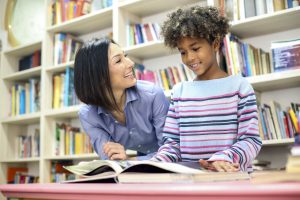 Teacher providing one-on-one reading support to an elementary student.