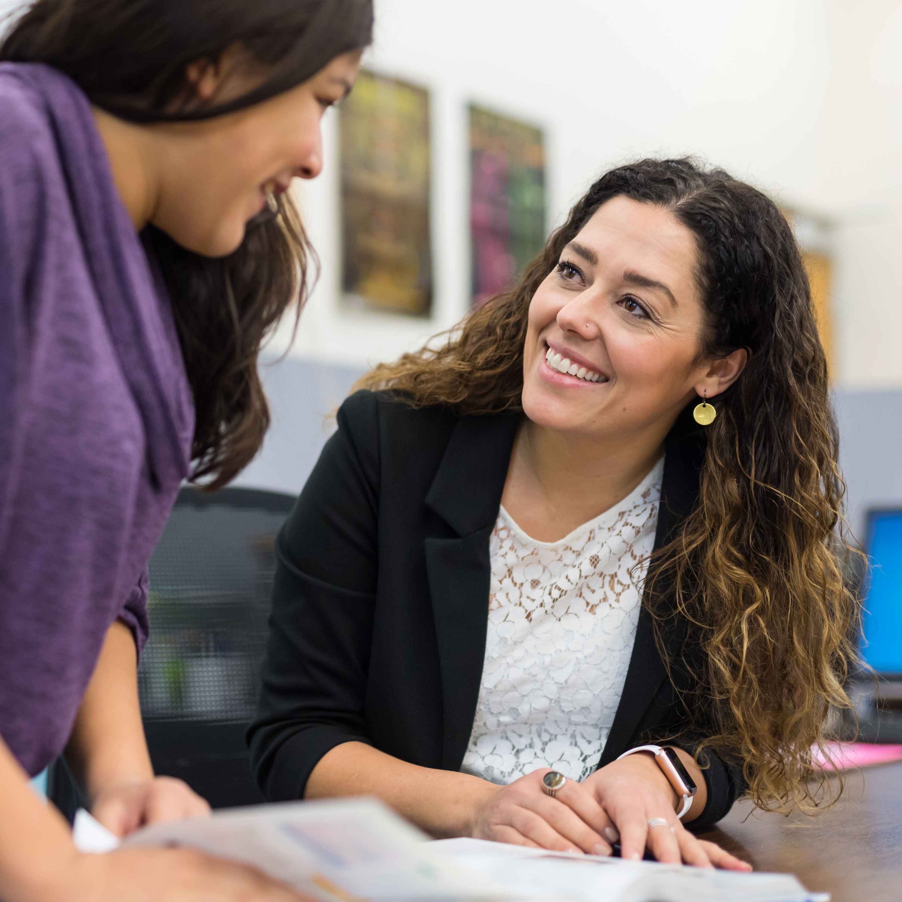 An advisor speaks with a student while reviewing class catalog.