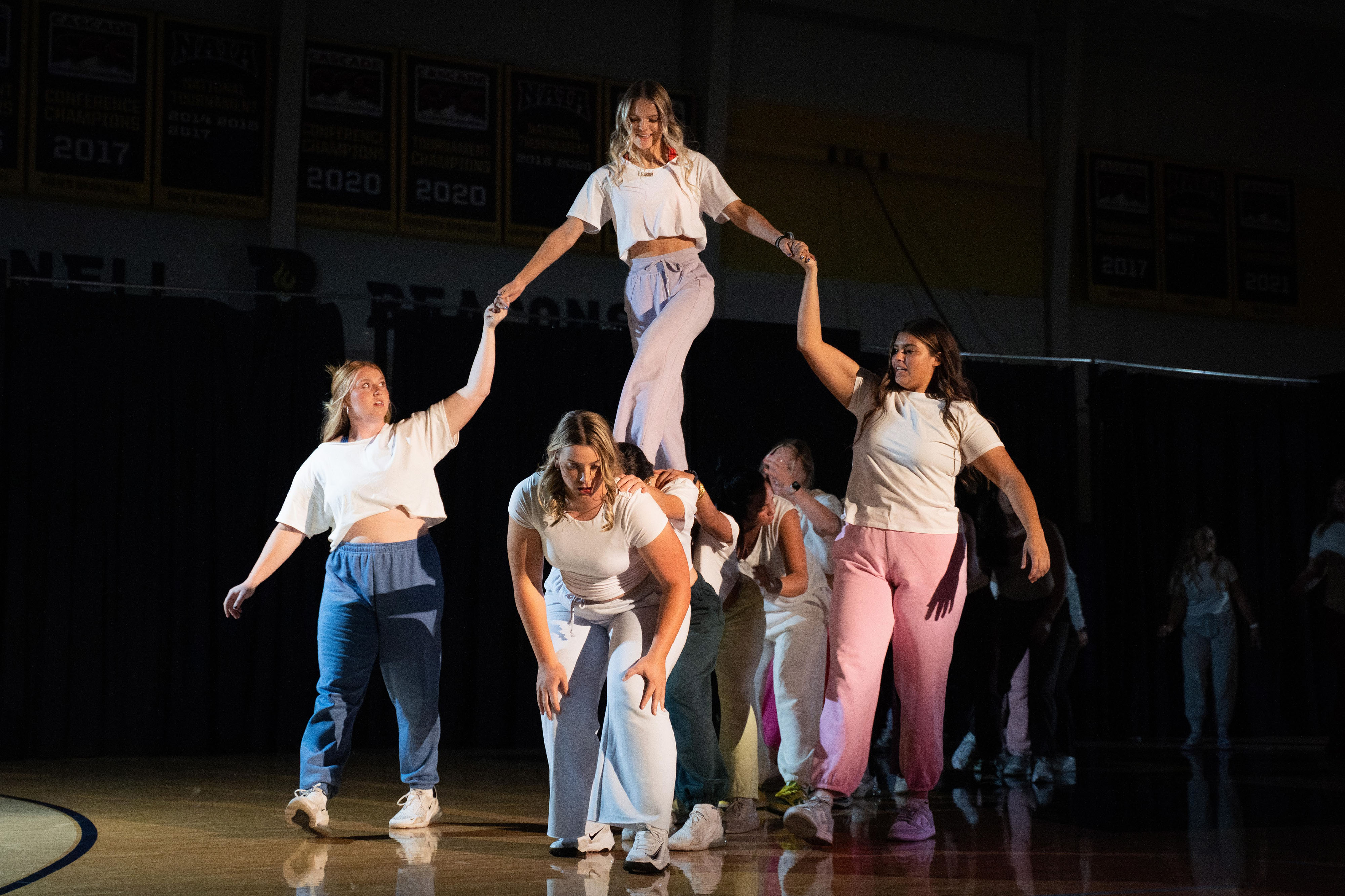 Softball team performing at Beacon Madness dance routine creating a pyramid of students.