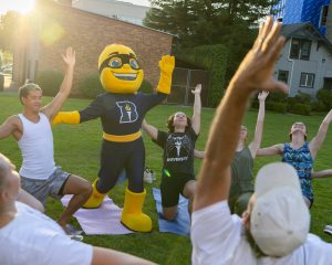Bushnell University's Beacons mascot participating in an outdoor student life activity with students on campus.