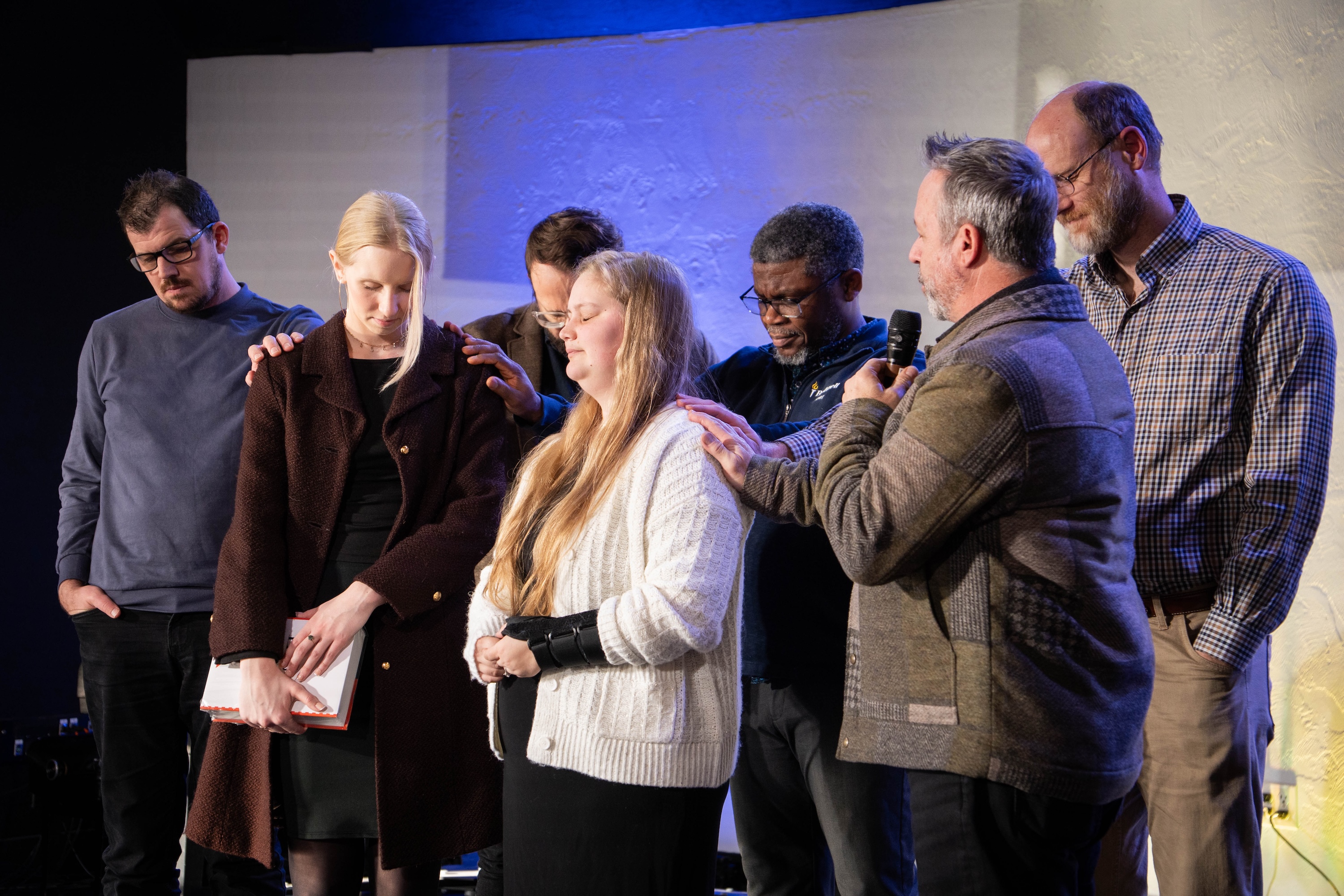 Bushnell University faculty and staff pray over students during a campus gathering, reflecting the university's Christ-centered community.