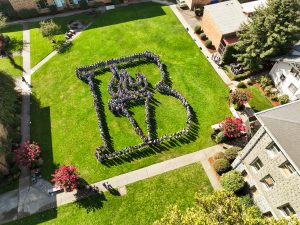 Aerial view of Bushnell University students and employees forming the Bushnell torch on the campus lawn.