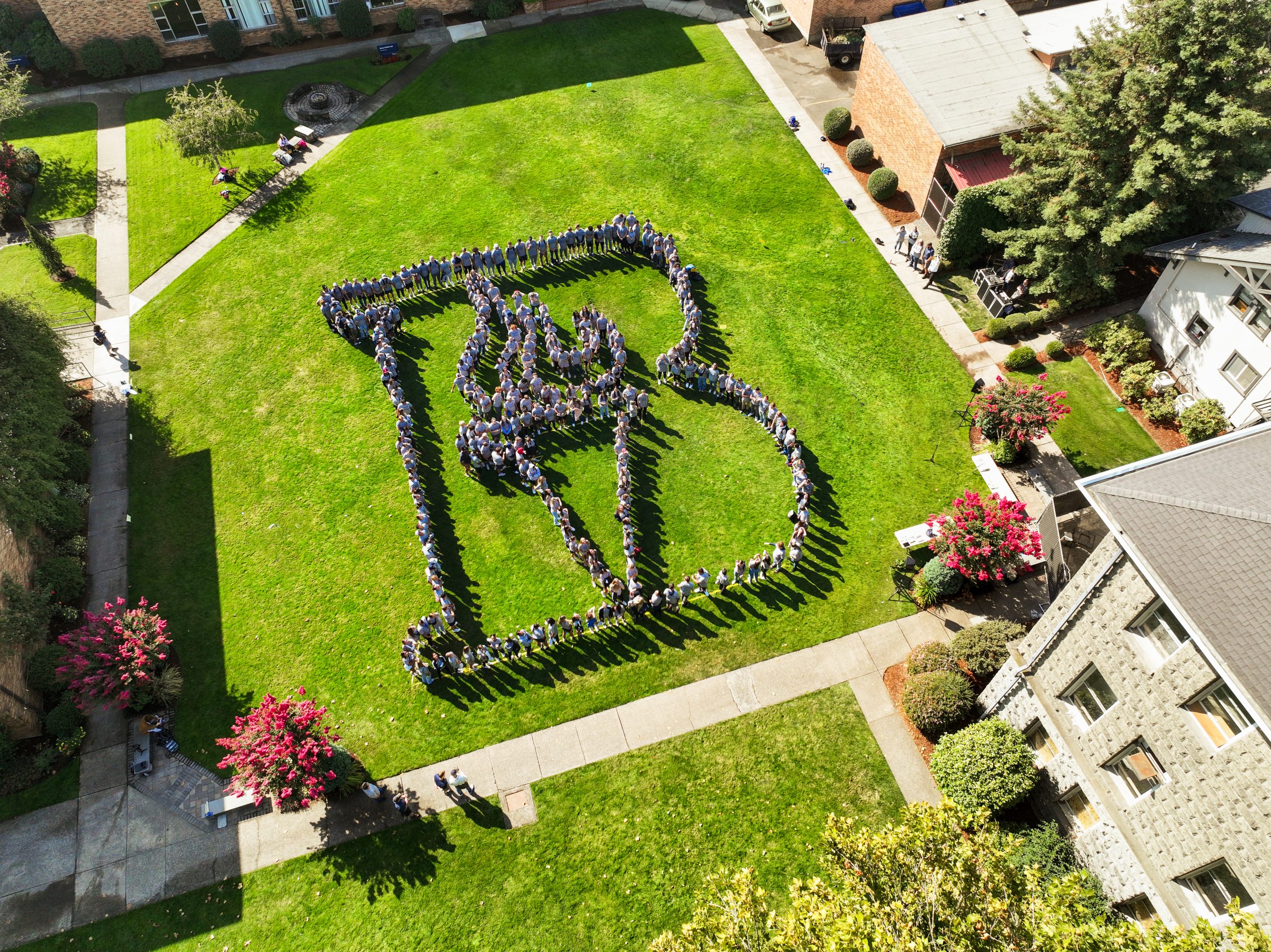 Aerial view of Bushnell University students and employees forming the Bushnell torch on the campus lawn.