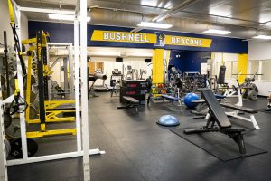Wide view of Bushnell University's fitness center featuring free weights, training equipment, and cardio machines.