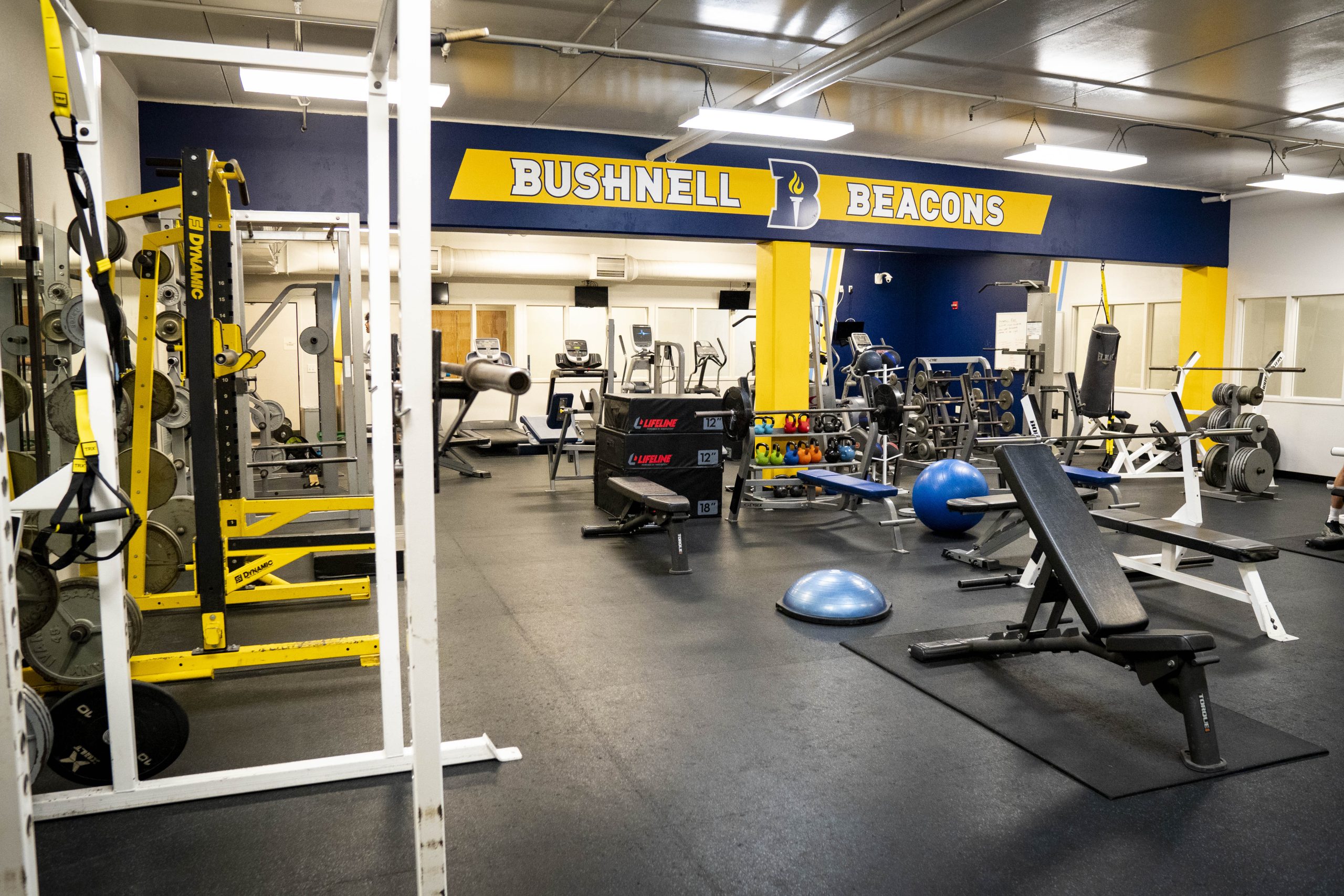 Wide view of Bushnell University's fitness center featuring free weights, training equipment, and cardio machines.