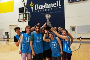 Bushnell University students celebrate their intramural basketball championship with the championship trophy in Morse Center.