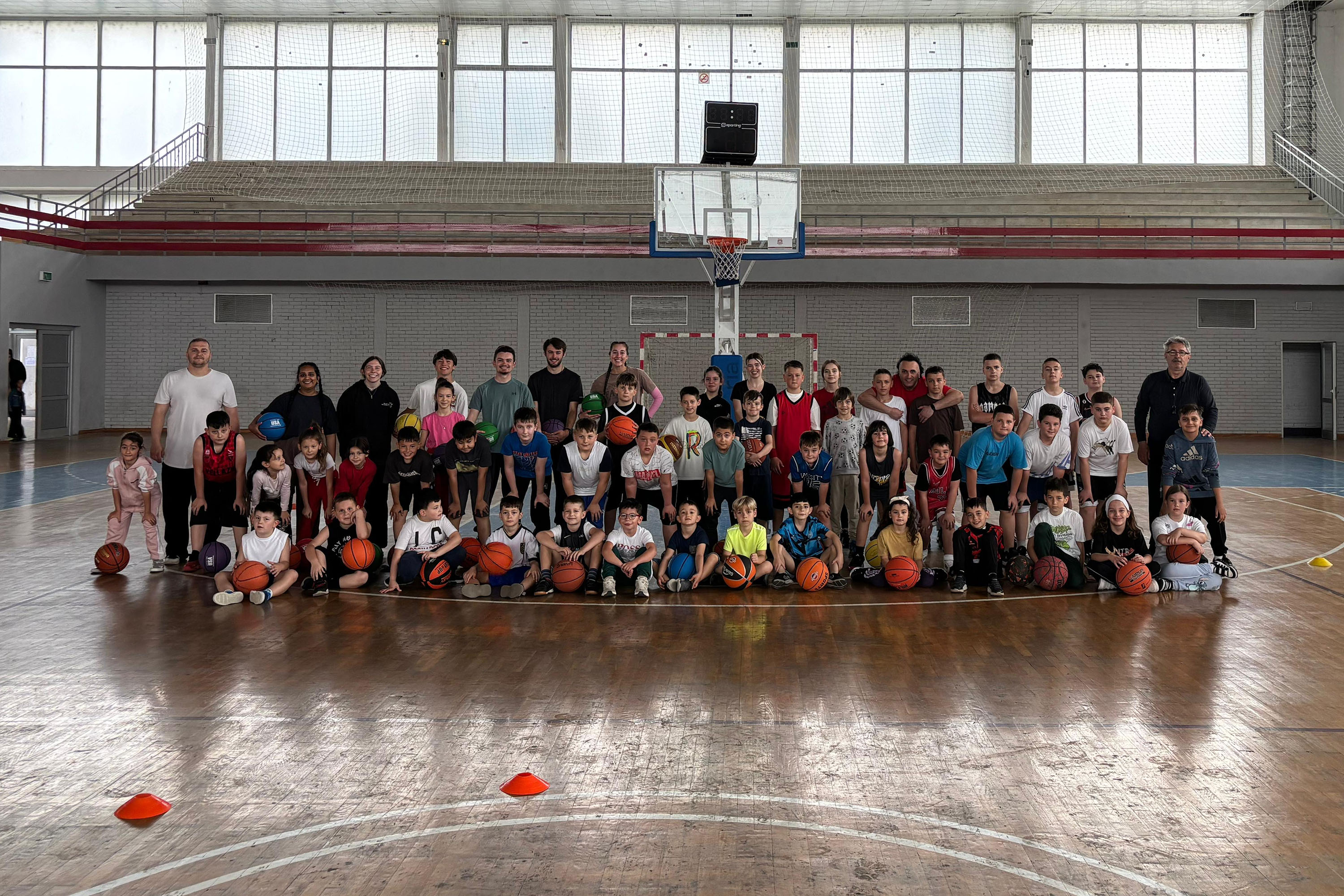 Kosovo mission trip team group photo with large group of children basketball players in a gym.