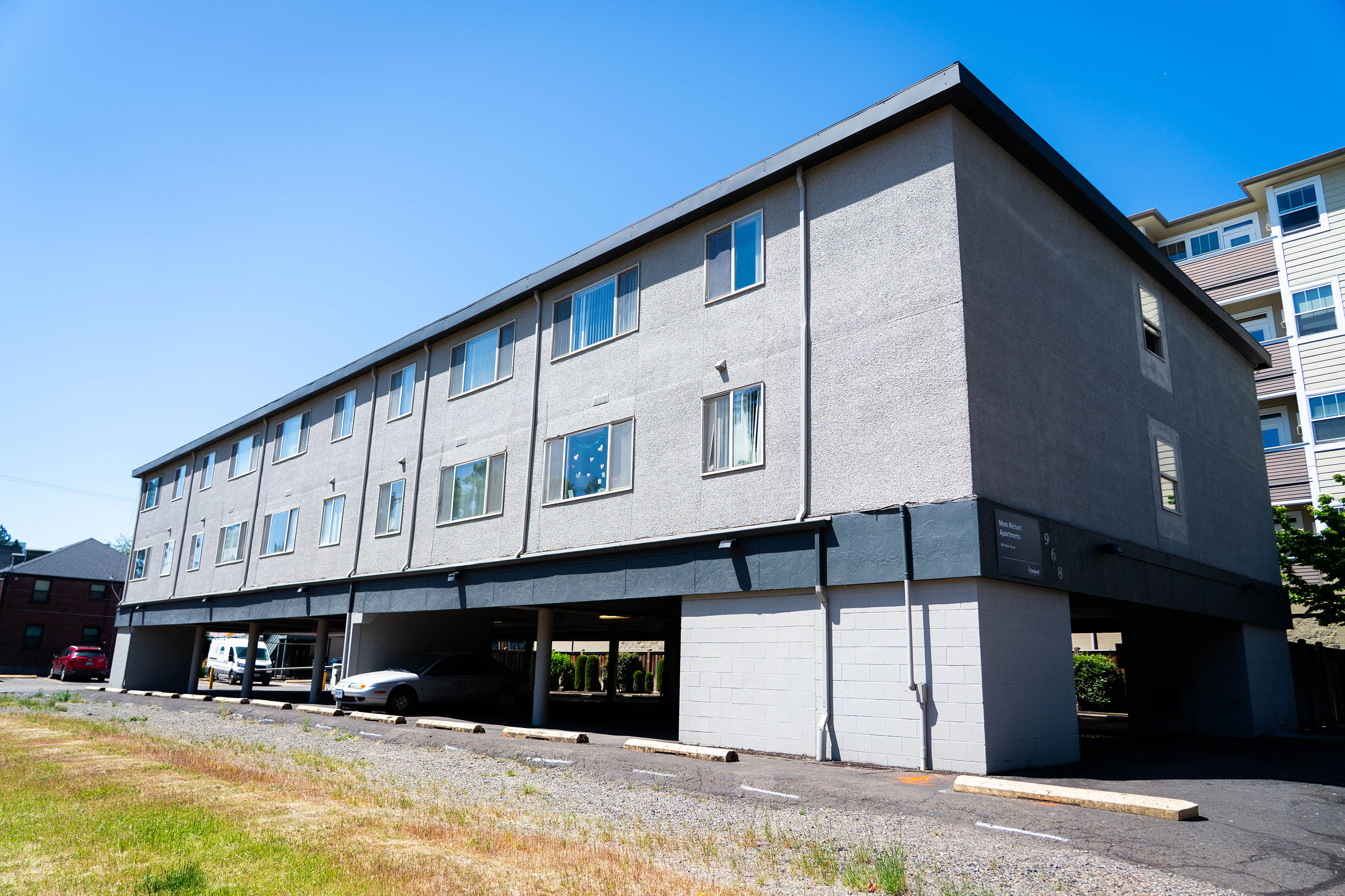 A light grey two floor student apartment building with an open parking garage below it.