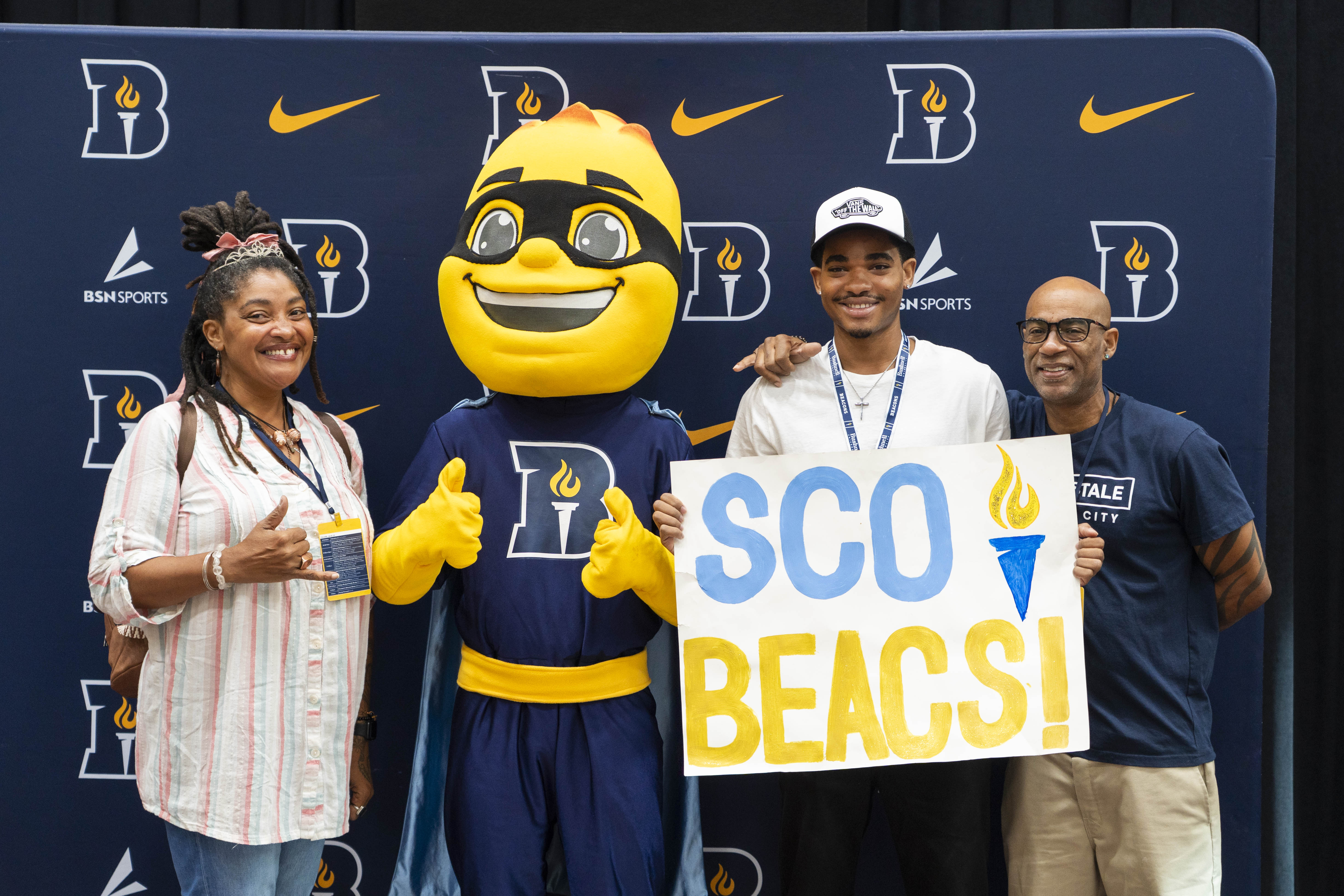 A new student and their family pose with Bushnell University mascot, Iggy Beacon, at Orientation.