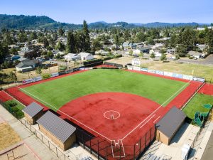 Aerial view of Rich Schwab Field, the home of Bushnell University Softball, featuring an all-turf field, dugouts, scoreboard, and surrounding Eugene landscape.