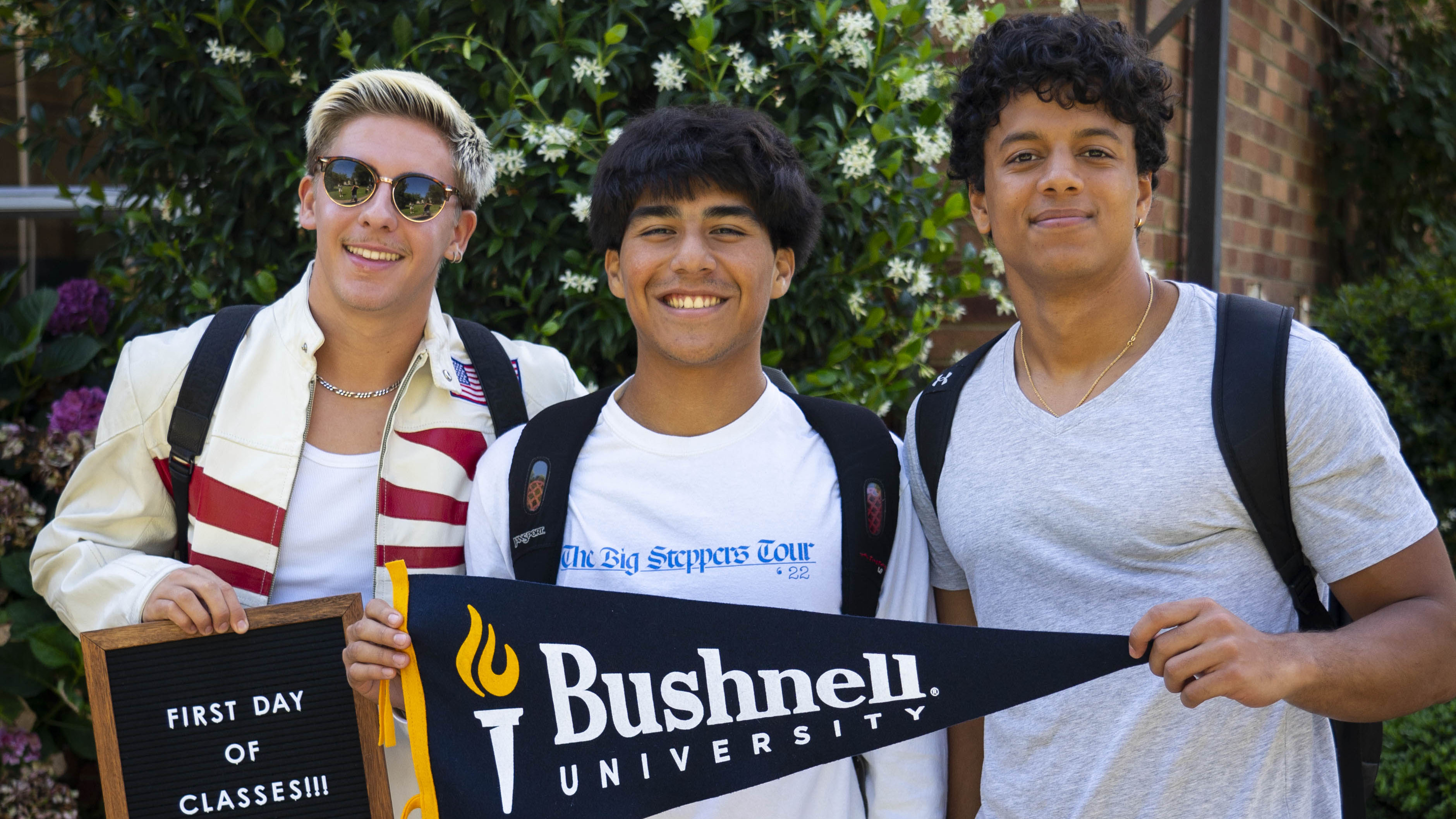 Group of students holding up a pennant and first day of classes sign
