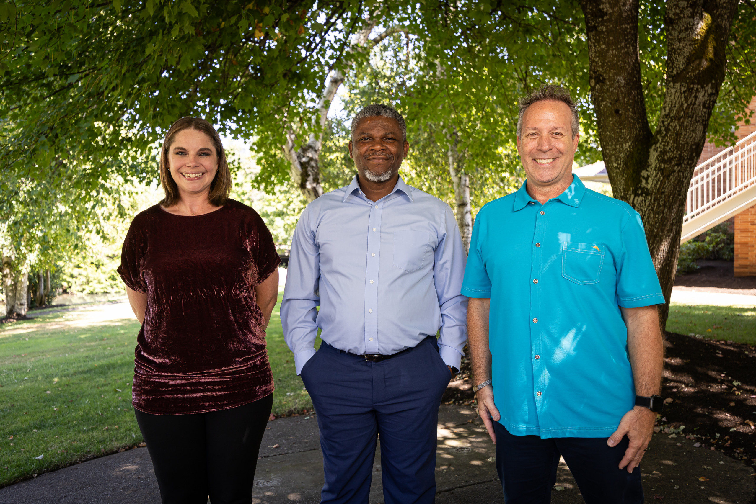 Three Bushnell University leaders pose outdoors on campus.