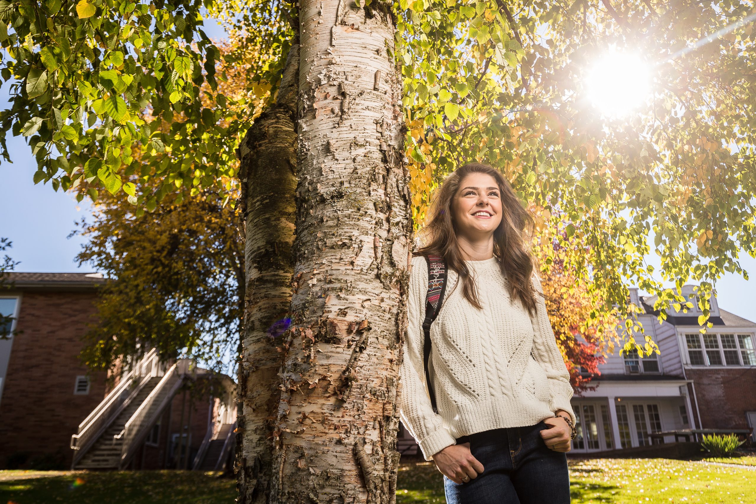 Student walking across Bushnell University's campus beneath autumn trees in Eugene, Oregon.