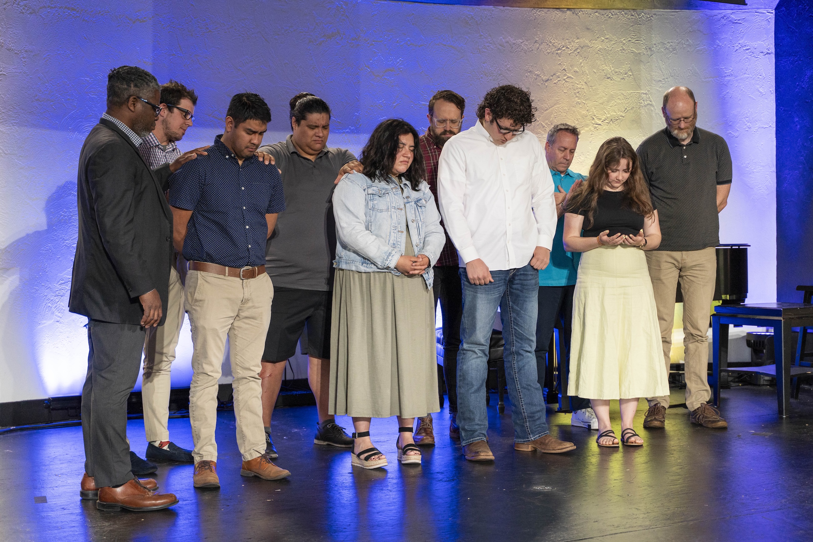 Bushnell University students, faculty, and staff gather on stage in prayer during a campus event.