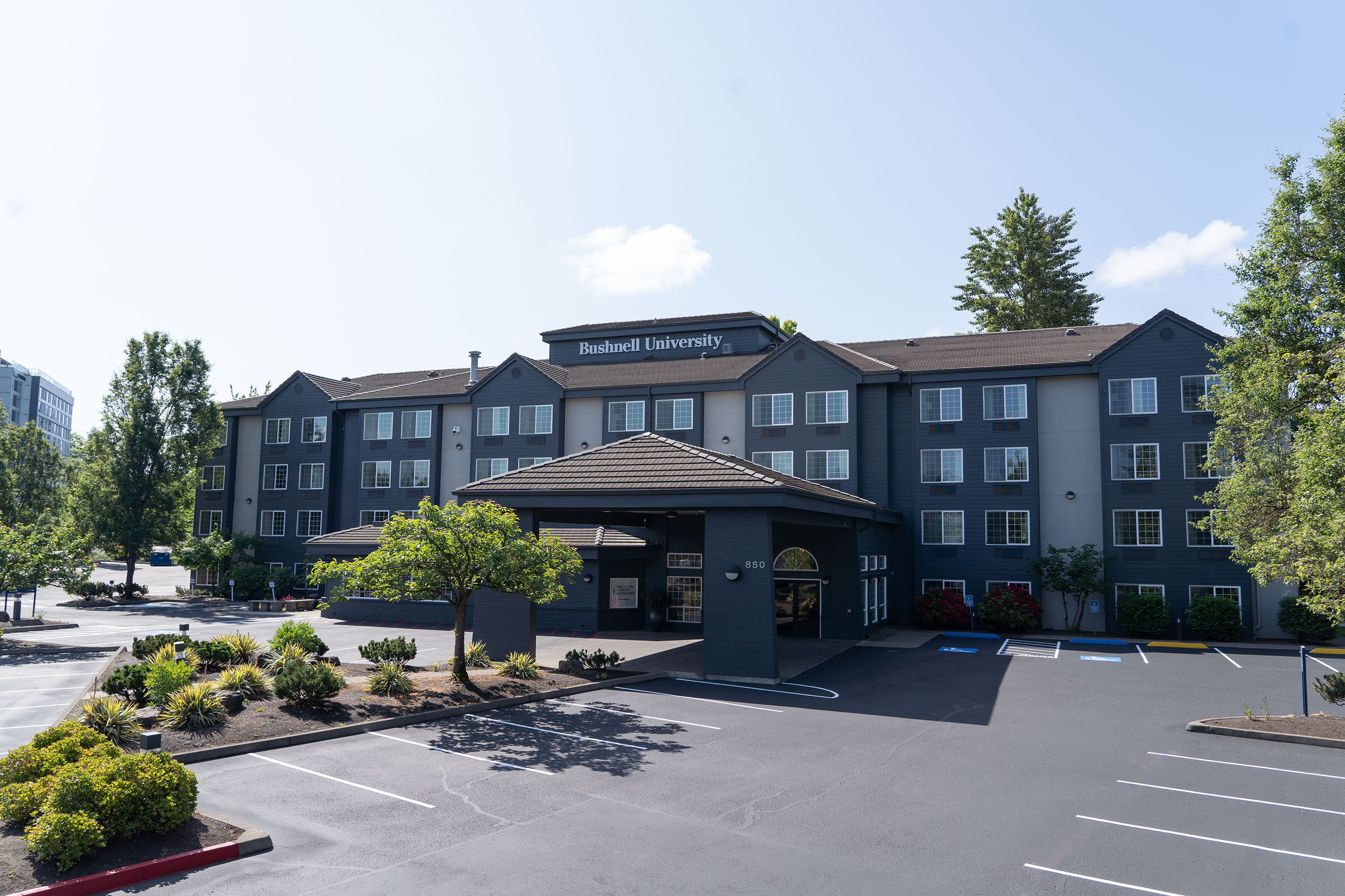 A photo of a blue gray painted, four floor dorm building with Bushnell University letters on top.