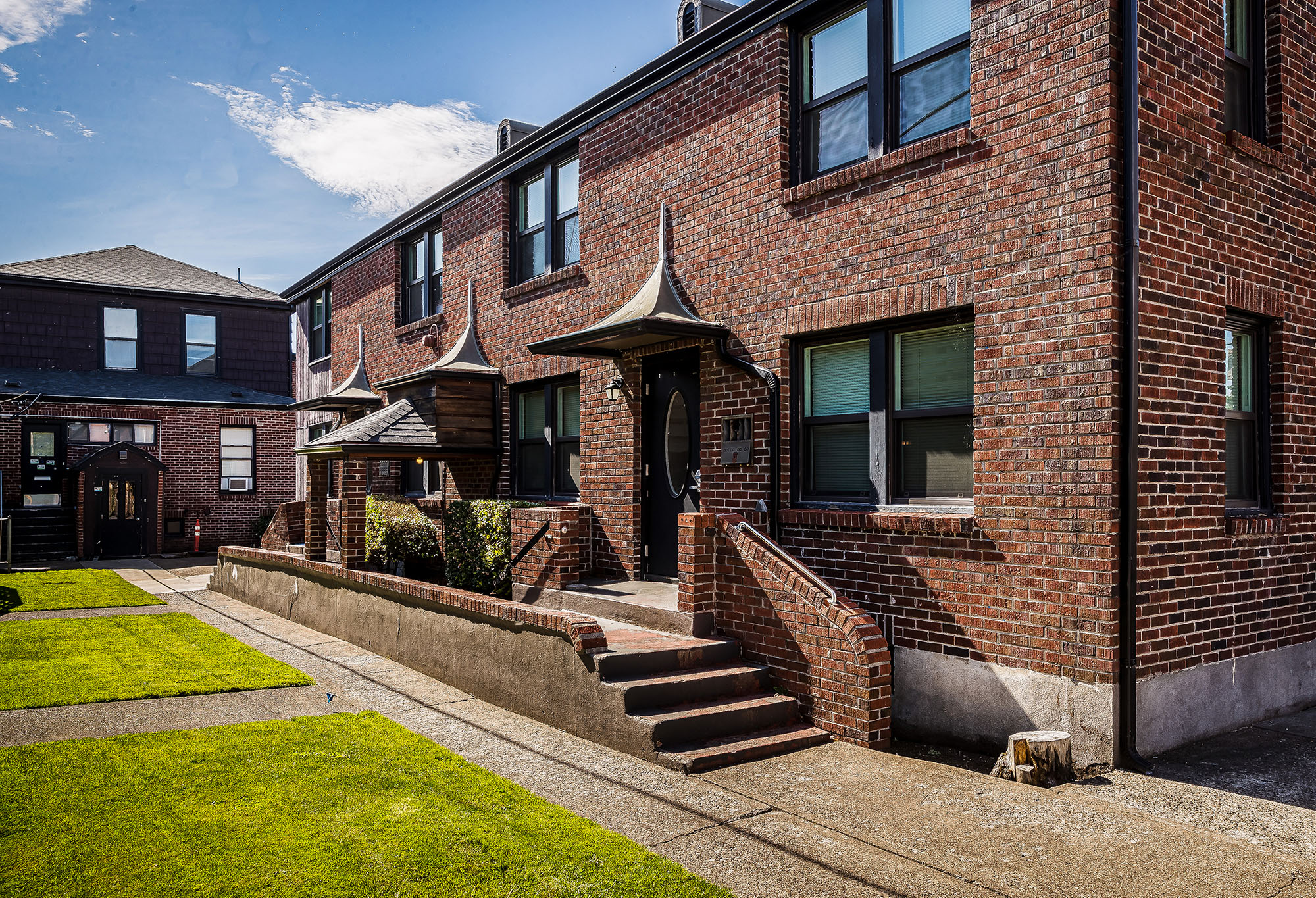 An orange and brown brick student apartment building with a grassy area.