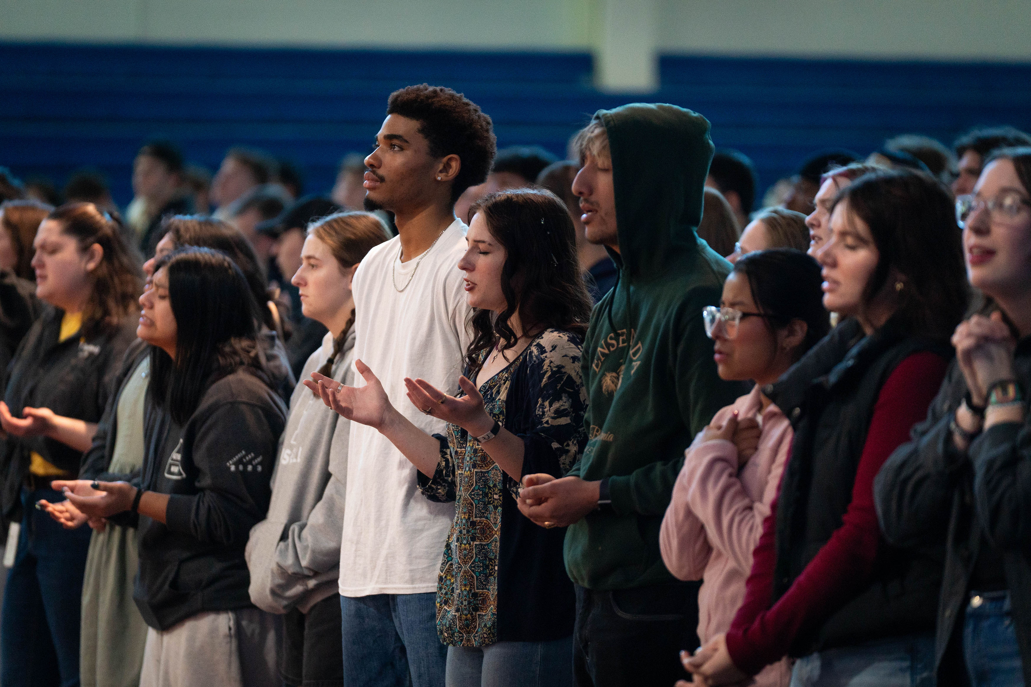 A row of multi-ethnic students worship and give praise during Chapel.